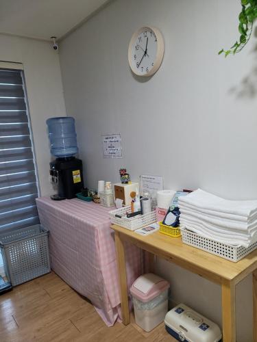 a table with a clock on the wall and a table with items at Incheon Intl Airport ANN Guest House in Incheon