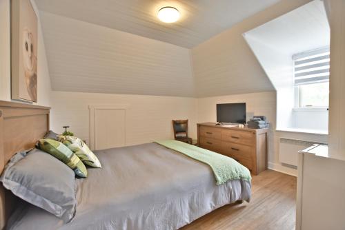 a bedroom with a bed and a dresser and a television at Chambre 305 de l'hôtel Victoria confortable et moderne in Saint-Pascal