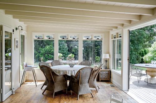 a dining room with a table and chairs and windows at Macksville Cottage Robertson in Robertson