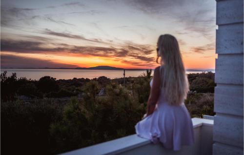 a girl standing on a ledge watching the sunset at Villa Petra Pag in Borovići