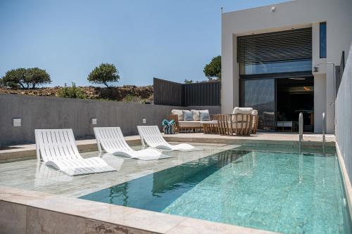 a swimming pool with two chairs and a swimming pool at Nature's Den in Frangokastello