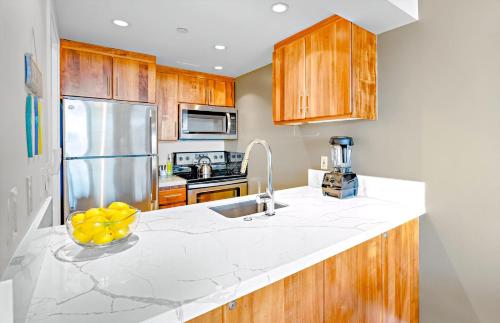 a kitchen with wooden cabinets and a counter top at The Whaler By Maui Resort Rentals in Lahaina