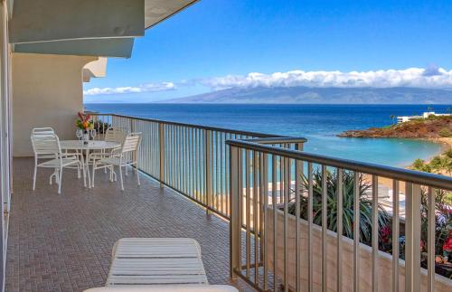 a balcony with a table and chairs and the ocean at The Whaler By Maui Resort Rentals in Lahaina
