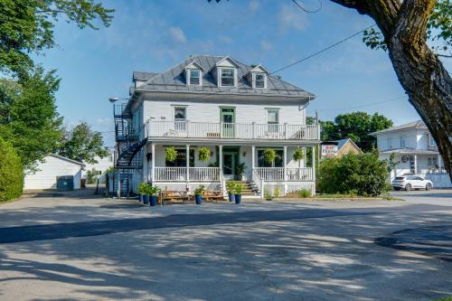 a white house with a porch on a street at Chambre 304 de l'hôtel Victoria confortable et moderne in Saint-Pascal