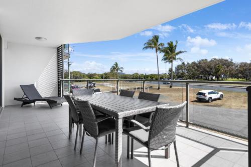 a table and chairs on a balcony with a view of a car at Beaches on Lammermoor Apartments in Yeppoon