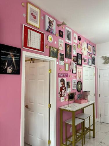 a room with a pink wall with pictures and a desk at The Swift Lake House in Somerset