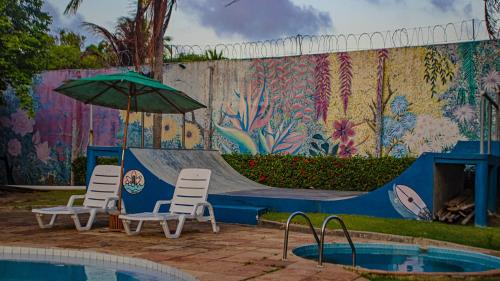 a pool with two chairs and an umbrella and a skate ramp at Flow Guest House in Salinópolis
