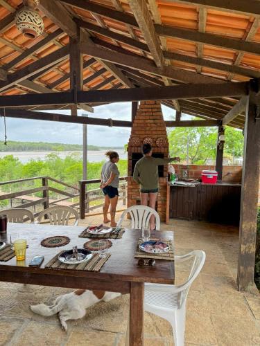 two people standing in a kitchen with a table at Flow Guest House in Salinópolis