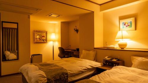 a hotel room with two beds and a desk at Suizansou in Toyooka