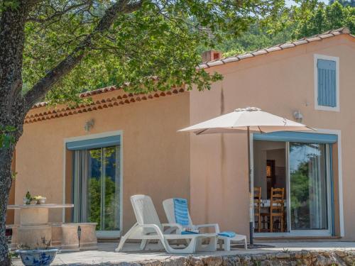 two chairs and an umbrella in front of a house at Verdon in Aiguines
