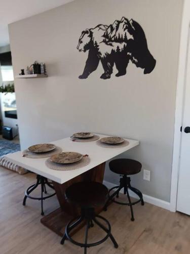 a table with four chairs and a bear on the wall at The Bears Den at the Lake in Somerset