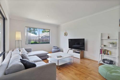 a living room with a couch and a tv at Across the Way, golf and beach heaven in Dunsborough