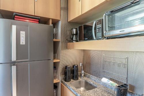 a kitchen with a stainless steel refrigerator and a sink at Flat ou Bangalo Luxo Beach Class Beira Mar Muro Alto in Porto De Galinhas