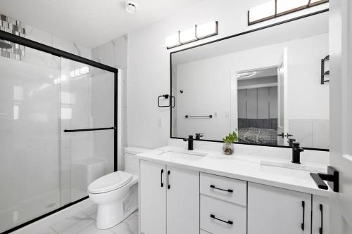 a white bathroom with a toilet and a mirror at The Happy place - Luxurious, Cozy and Modern Home with Air-condition, Netflix, Free Parking close to Airport and West Edmonton Mall in Edmonton