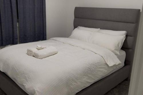 a white bed with two towels on top of it at The Happy place - Luxurious, Cozy and Modern Home with Air-condition, Netflix, Free Parking close to Airport and West Edmonton Mall in Edmonton