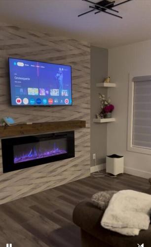 a living room with a flat screen tv above a fireplace at The Happy place - Luxurious, Cozy and Modern Home with Air-condition, Netflix, Free Parking close to Airport and West Edmonton Mall in Edmonton