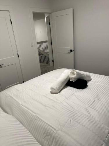 a white bed with a towel on top of it at The Happy place - Luxurious, Cozy and Modern Home with Air-condition, Netflix, Free Parking close to Airport and West Edmonton Mall in Edmonton
