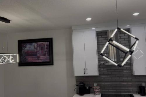 a kitchen with white cabinets and a chandelier at The Happy place - Luxurious, Cozy and Modern Home with Air-condition, Netflix, Free Parking close to Airport and West Edmonton Mall in Edmonton