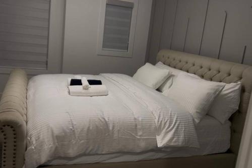 a white bed with a towel on top of it at The Happy place - Luxurious, Cozy and Modern Home with Air-condition, Netflix, Free Parking close to Airport and West Edmonton Mall in Edmonton