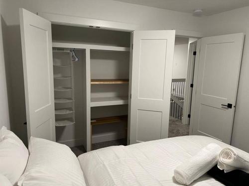 a bedroom with a bed and a closet with shelves at The Happy place - Luxurious, Cozy and Modern Home with Air-condition, Netflix, Free Parking close to Airport and West Edmonton Mall in Edmonton