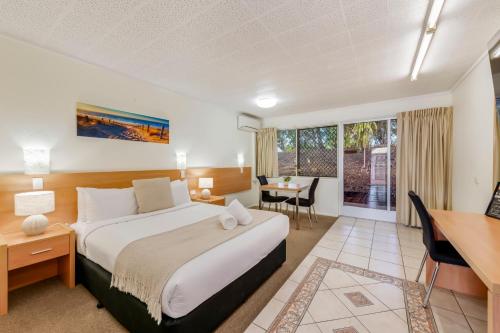 a hotel room with a bed and a desk and a table at Bundaberg International in Bundaberg