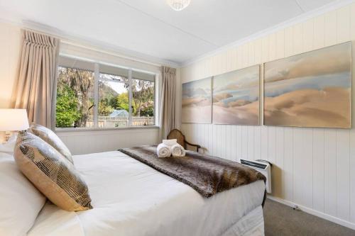 a bedroom with a large white bed with a window at Central Arrowtown - 4 Beds and Hot Tub! in Arrowtown