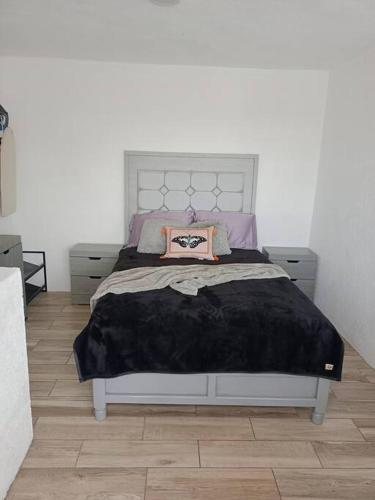 a bedroom with a bed with a black blanket on it at Casita azul in Morelia
