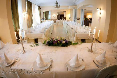 un salón de banquetes con mesas blancas, sillas y velas en Hotel Roma, en Kalisz