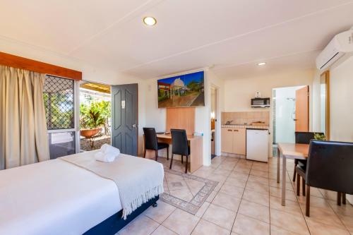 a hotel room with a bed and a dining room at Bundaberg International in Bundaberg