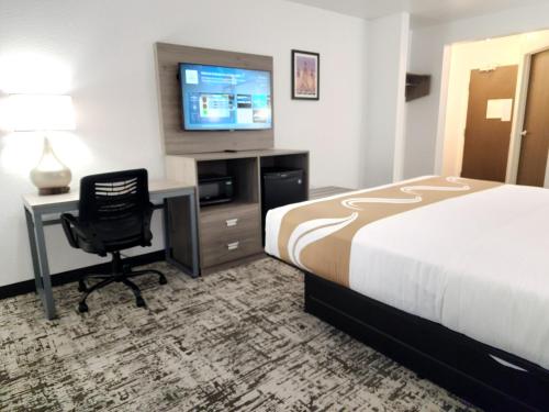 a hotel room with a bed and a desk and a television at Quality Inn & Suites Denver International Airport in Denver