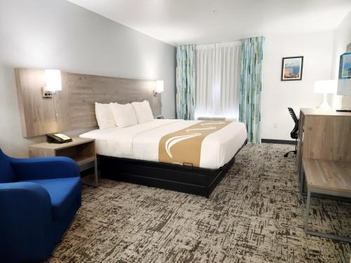 a hotel room with a bed and a blue couch at Quality Inn & Suites Denver International Airport in Denver