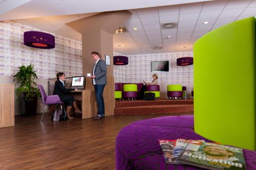 a man standing in a waiting room with two people at Mercure Hotel Hamburg am Volkspark in Hamburg