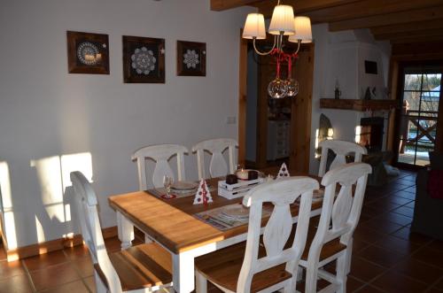 a dining room with a wooden table and white chairs at Zagroda Krasna in Polańczyk