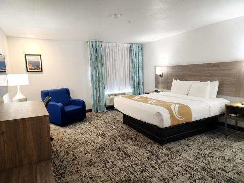 a hotel room with a bed and a blue chair at Quality Inn & Suites Denver International Airport in Denver