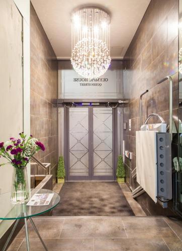 a lobby with a door and a table and a chandelier at PREMIER SUITES PLUS Glasgow George Square in Glasgow