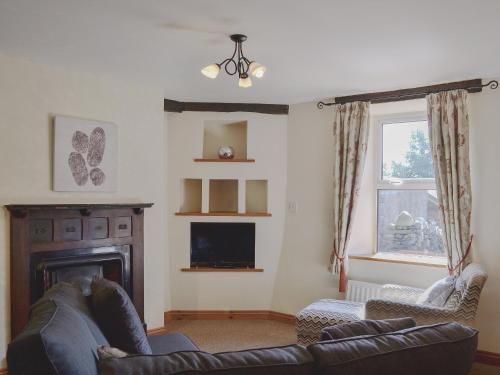 a living room with a couch and a fireplace at Brackendale Cottage - Uk1335 in Threlkeld