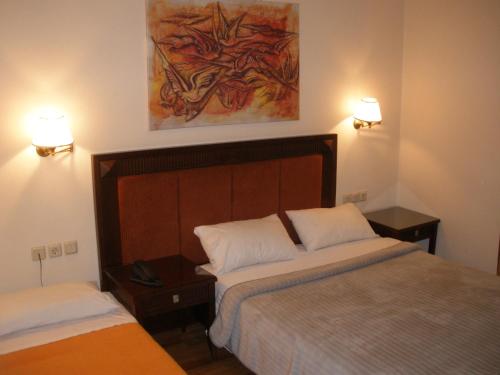 una camera con due letti e due luci sul muro di Pelias Hotel a Portariá