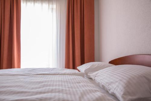 a bed with white sheets and a window at Hotel Knez in Kupres