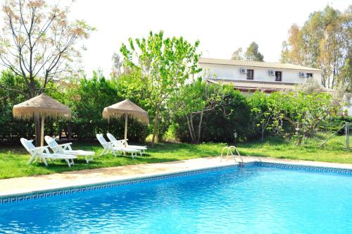 a swimming pool with two lawn chairs and umbrellas at Hotel Rural La Paloma in Villanueva de Tapia