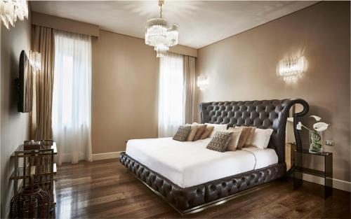 a bedroom with a large bed with a black leather headboard at LE RÊVE DE NAIM Roma in Rome