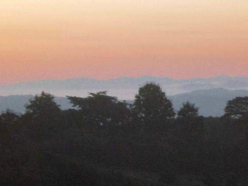 a sunset with trees and mountains in the background at Rai Phuchat in Ban Pa Thon