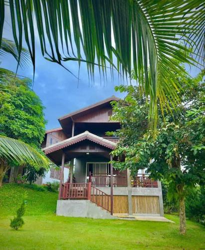 a house with a green yard with a tree at Rai Phuchat in Ban Pa Thon