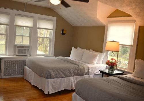two beds in a room with two windows at The House Hotels - Acadia Farms in Northfield