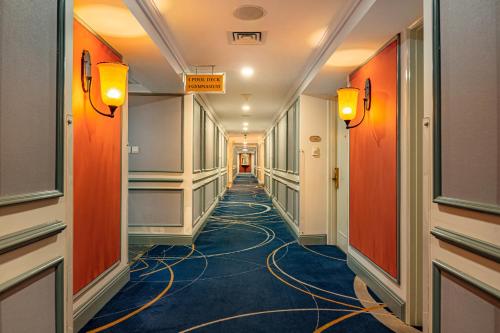a long hallway with orange walls and blue carpet at Saigon Prince Hotel in Ho Chi Minh City