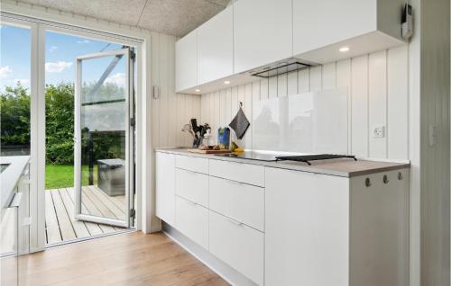 a kitchen with white cabinets and a large window at Nice Home In Frørup With Kitchen in Tårup