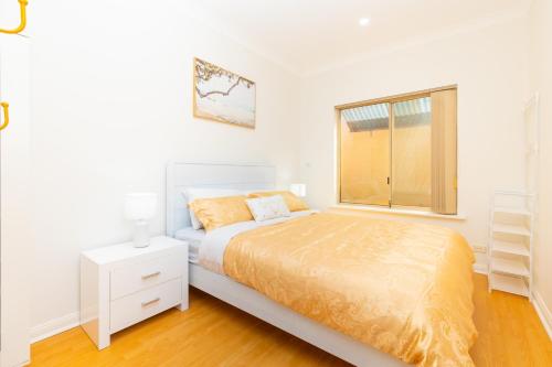 a white bedroom with a bed and a window at Glenelg House Modern 5QBed,1cot,3Bth, 4TV,FastWIFI in Glenelg
