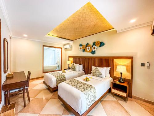 a bedroom with two beds and a table and a desk at Ghana Villa Seminyak by GenuineHost in Seminyak