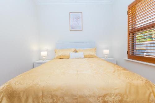 a large bed in a white room with two lamps at Glenelg House Modern 5QBed,1cot,3Bth, 4TV,FastWIFI in Glenelg
