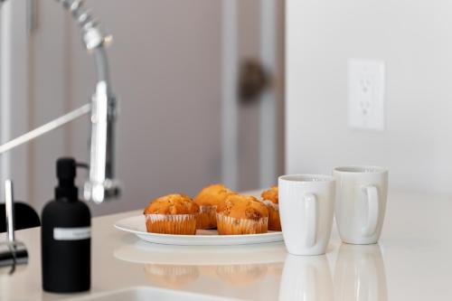 a plate of muffins on a table next to two cups at Luxury Furnished Apartments by Hyatus Downtown at Yale in New Haven