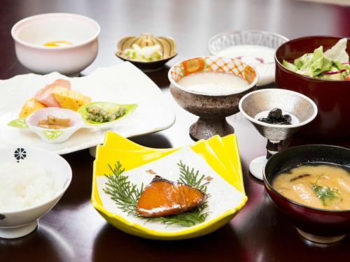 een tafel met kommen en borden met voedsel bij Hatago Sakura in Kokonoe